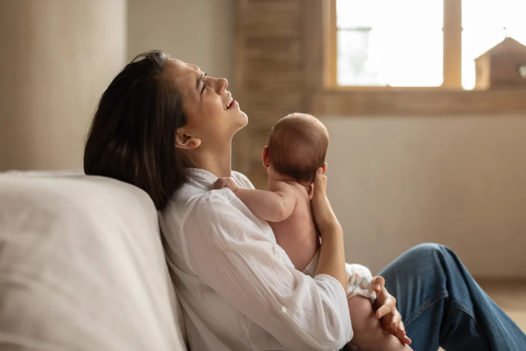 A Mother holding her baby with expressions, signs of baby blues vs postpartum depression in new parents